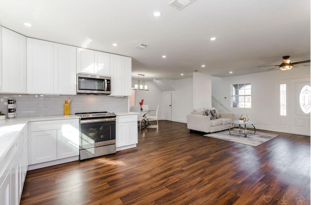 kitchen with white cabinetry, dark hardwood / wood-style flooring, decorative backsplash, hanging light fixtures, and stainless steel appliances