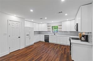 kitchen featuring tasteful backsplash, white cabinetry, dishwashing machine, white refrigerator with ice dispenser, and dark wood-type flooring