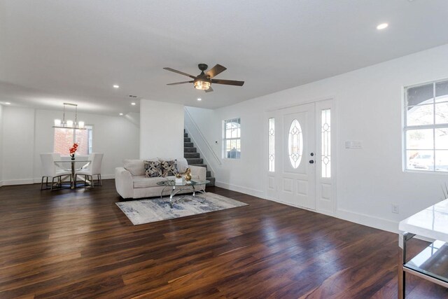 entrance foyer with ceiling fan with notable chandelier, dark wood-type flooring, and a wealth of natural light