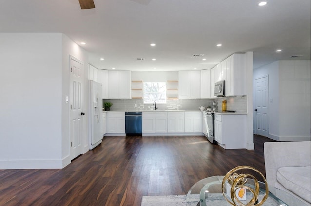 kitchen featuring appliances with stainless steel finishes, sink, white cabinets, decorative backsplash, and dark wood-type flooring