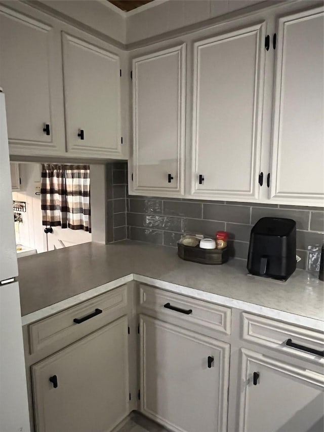 interior space featuring white cabinetry, light countertops, tasteful backsplash, and freestanding refrigerator