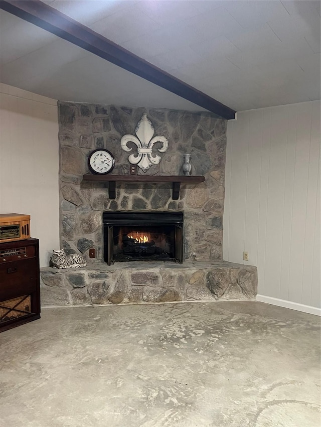 interior details with beam ceiling, a stone fireplace, and concrete floors