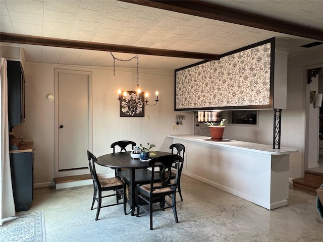 dining room featuring baseboards, beam ceiling, concrete floors, and a chandelier