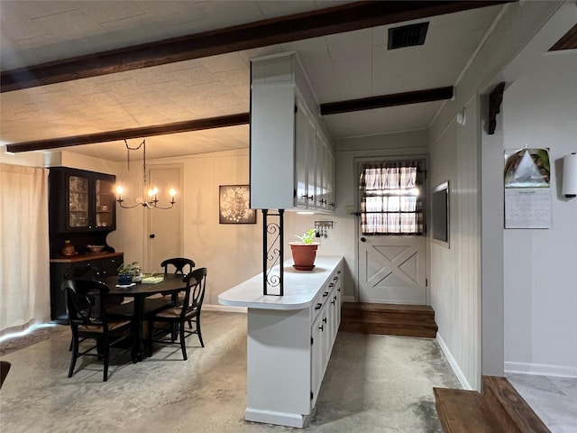 kitchen featuring visible vents, unfinished concrete floors, light countertops, beam ceiling, and a notable chandelier