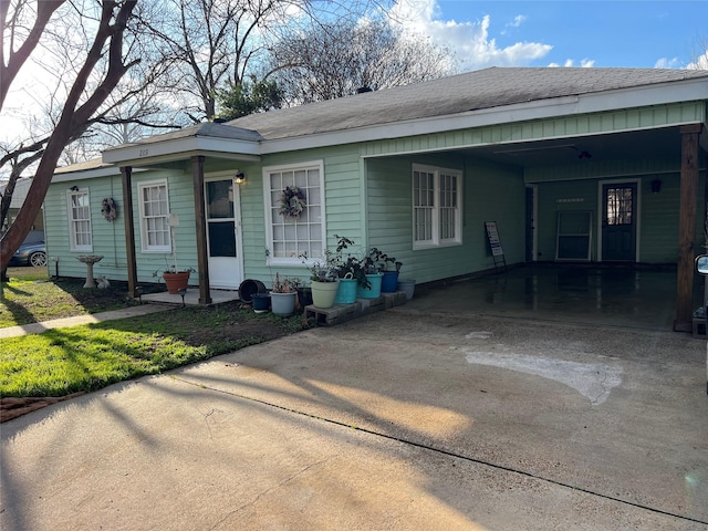 view of front of house with an attached carport, concrete driveway, and a shingled roof