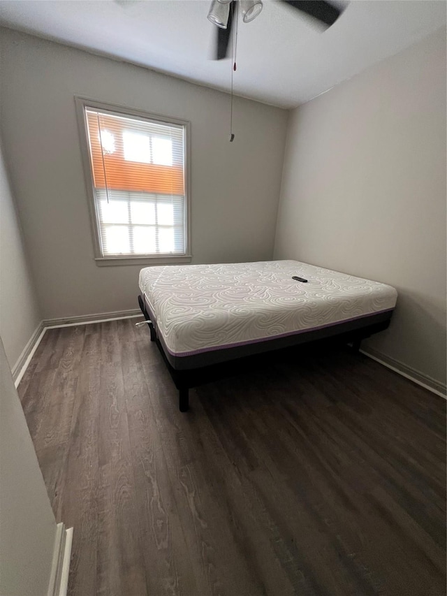 bedroom featuring dark wood-style floors, a ceiling fan, and baseboards