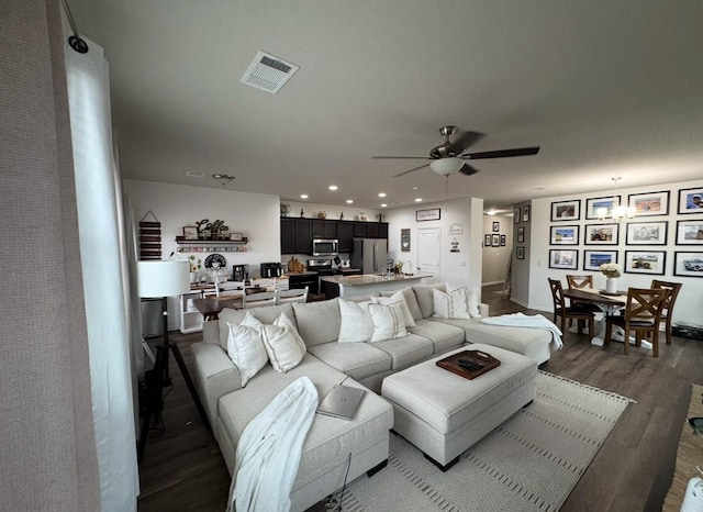 living room with dark wood-type flooring and ceiling fan with notable chandelier