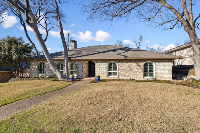 ranch-style home with a front yard, brick siding, and a chimney