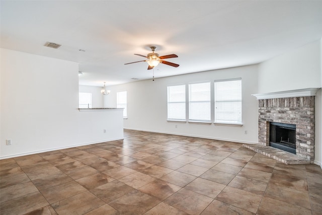 unfurnished living room featuring tile patterned flooring, ceiling fan with notable chandelier, and a fireplace