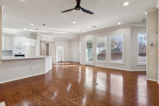 unfurnished living room featuring ornamental molding, a healthy amount of sunlight, and dark hardwood / wood-style floors