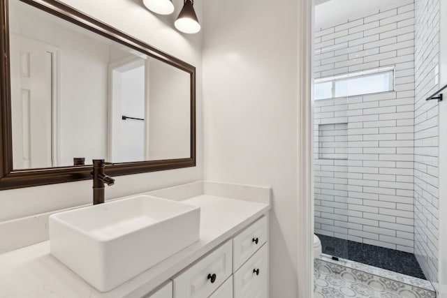 bathroom with vanity, toilet, and a tile shower