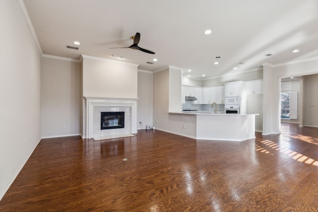 unfurnished living room with a tiled fireplace, dark hardwood / wood-style floors, and sink