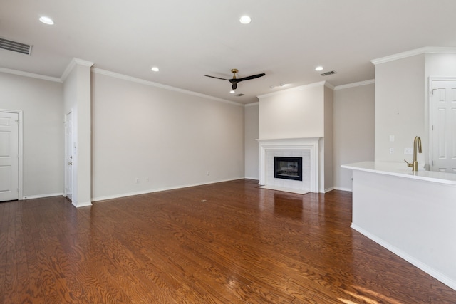 unfurnished living room featuring ceiling fan, crown molding, sink, and dark hardwood / wood-style flooring