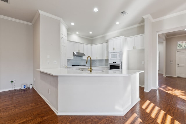 kitchen featuring white cabinetry, white microwave, dark hardwood / wood-style floors, kitchen peninsula, and stainless steel oven