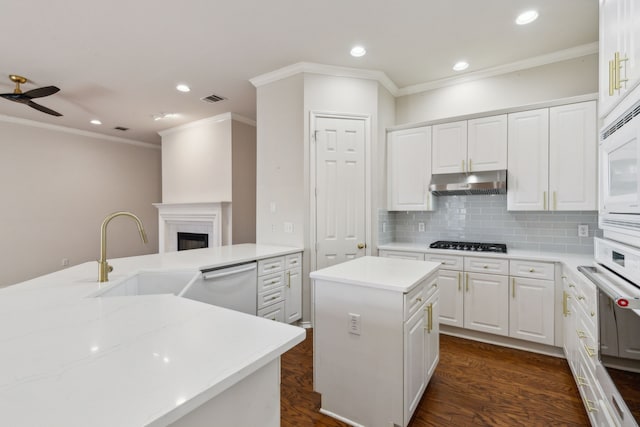 kitchen with white cabinetry, dishwashing machine, sink, and a kitchen island