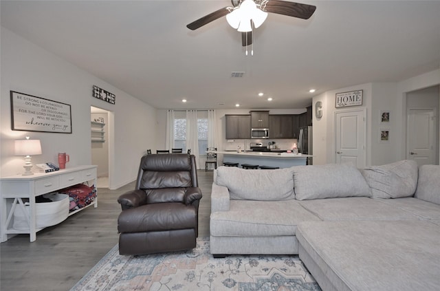 living room with light hardwood / wood-style floors and ceiling fan