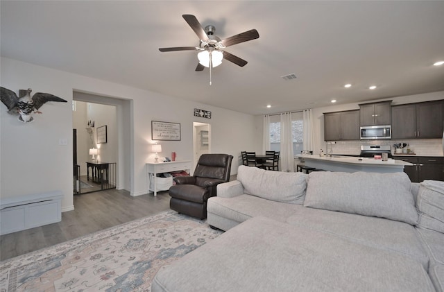 living room with sink, ceiling fan, and light hardwood / wood-style flooring