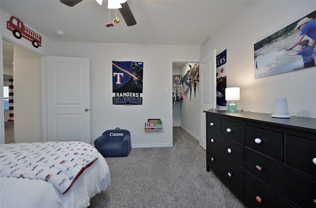 carpeted bedroom featuring a walk in closet, ceiling fan, and a closet