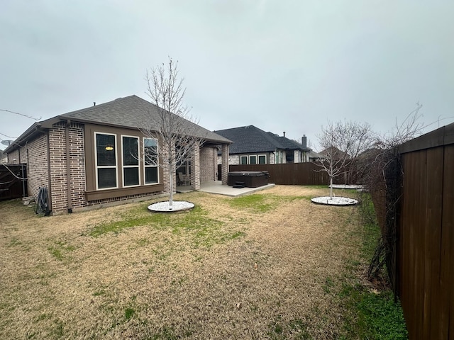 back of property featuring a yard, a hot tub, and a patio