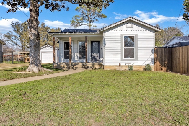 bungalow-style house with a garage, a porch, an outbuilding, and a front lawn