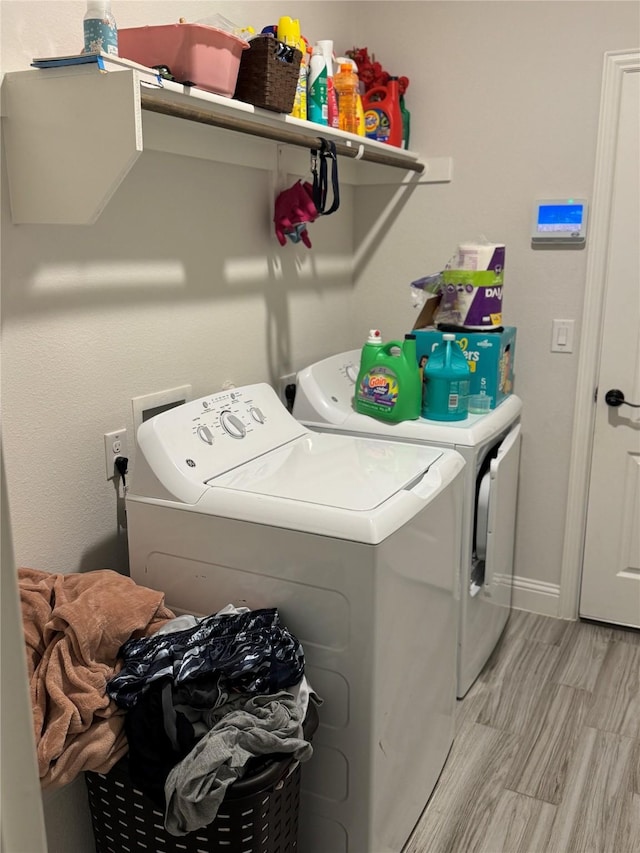 laundry area featuring washing machine and clothes dryer and light wood-type flooring