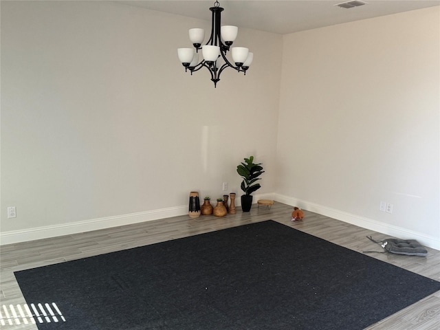 workout area featuring wood-type flooring and a notable chandelier