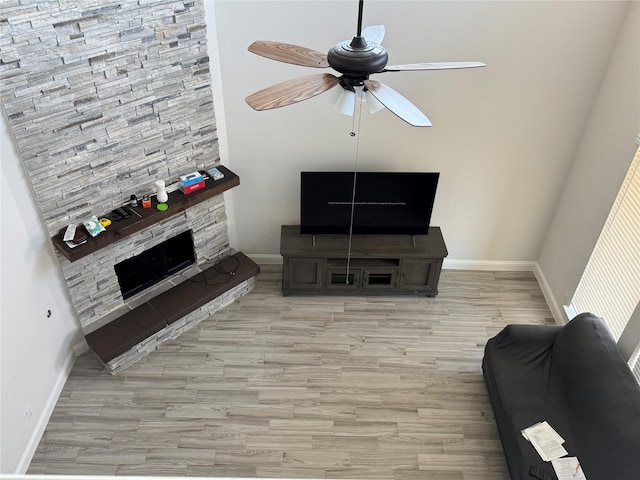 living room featuring light wood-type flooring, a fireplace, and ceiling fan