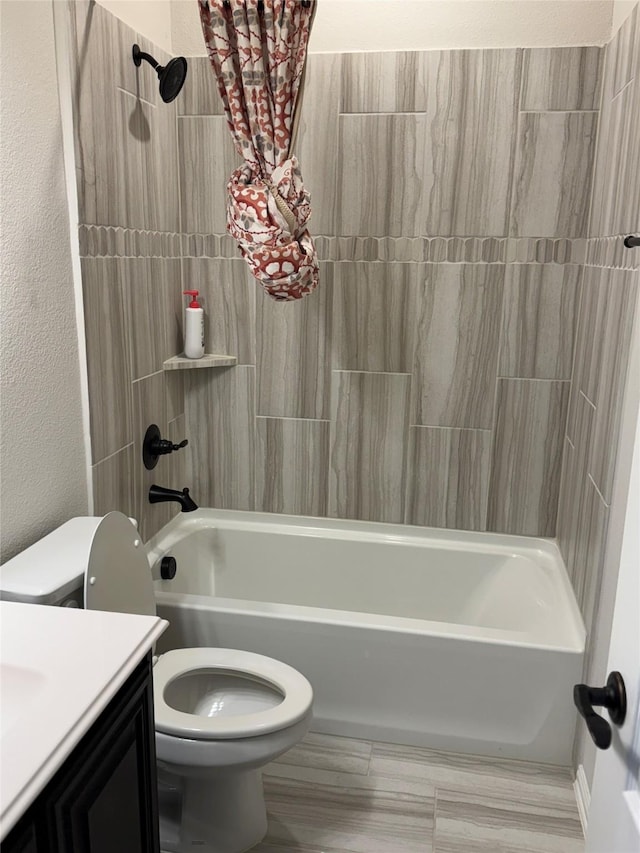 full bathroom with tiled shower / bath, vanity, and toilet