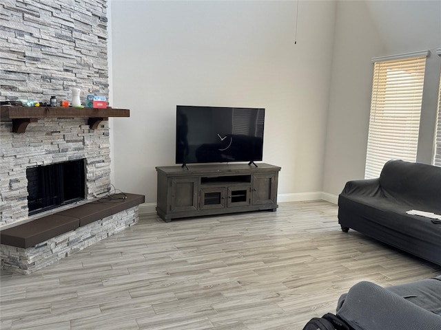 living room with a stone fireplace and light hardwood / wood-style floors