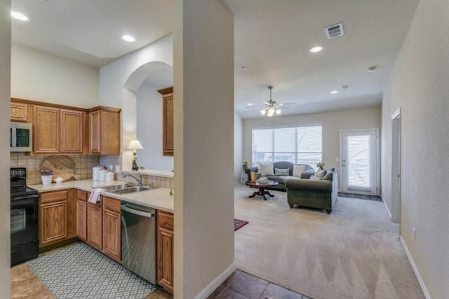 kitchen with appliances with stainless steel finishes, sink, decorative backsplash, light colored carpet, and ceiling fan