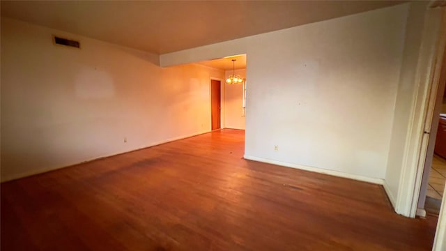 unfurnished room featuring wood-type flooring and a notable chandelier