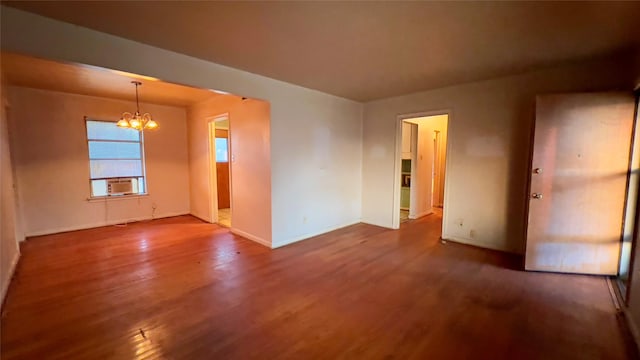 spare room with hardwood / wood-style flooring, cooling unit, and a notable chandelier