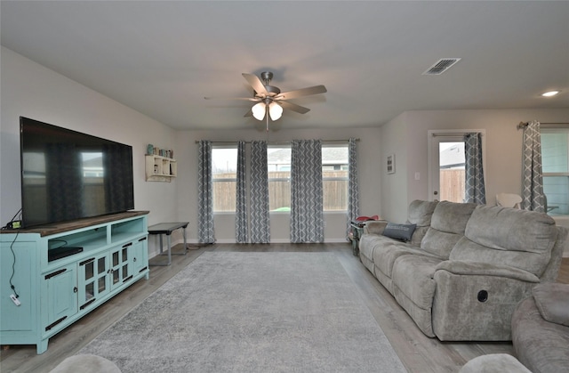 living room with light hardwood / wood-style flooring and ceiling fan