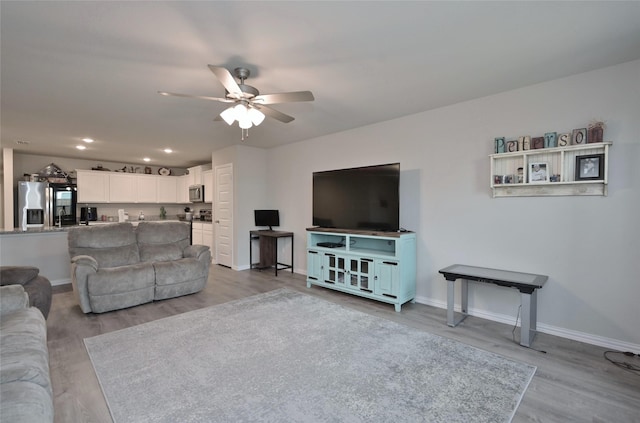 living room featuring ceiling fan and light hardwood / wood-style floors