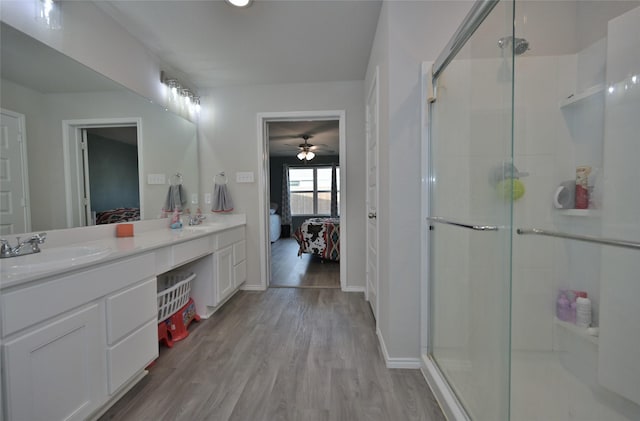 bathroom featuring ceiling fan, wood-type flooring, a shower with door, and vanity