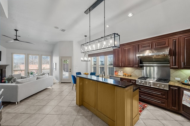 kitchen with stainless steel gas cooktop, tasteful backsplash, light tile patterned floors, dark stone countertops, and pendant lighting