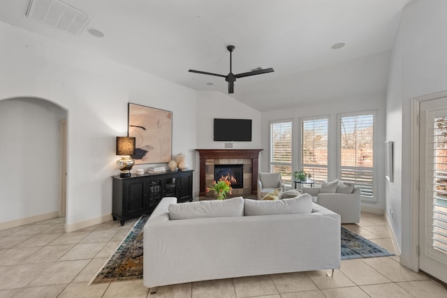 living room with a tiled fireplace, lofted ceiling, light tile patterned floors, and ceiling fan