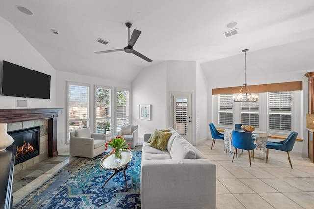 tiled living room featuring a tiled fireplace, ceiling fan with notable chandelier, and vaulted ceiling