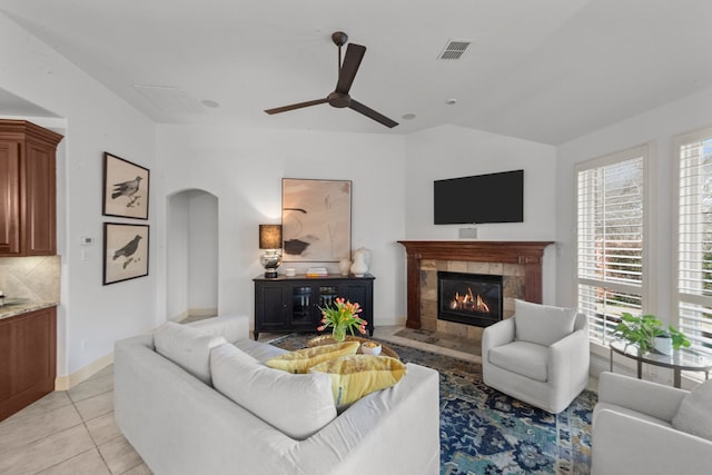 tiled living room featuring a tile fireplace, vaulted ceiling, and ceiling fan