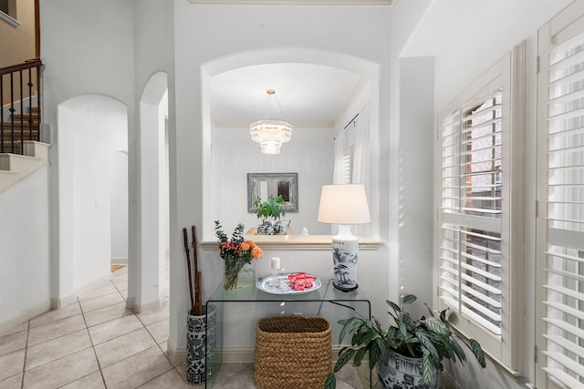 corridor featuring crown molding, a notable chandelier, and light tile patterned floors