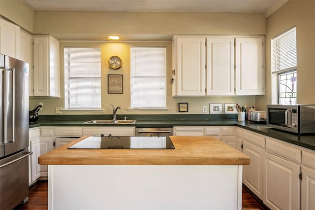 kitchen featuring stainless steel appliances, a kitchen island, sink, and white cabinets