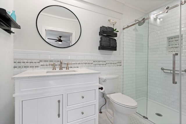 bathroom with vanity, a shower with shower door, toilet, and tile walls