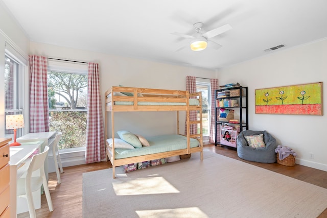 bedroom featuring ceiling fan, wood-type flooring, and multiple windows