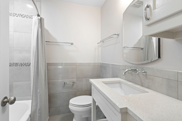 full bathroom with tile walls, vanity, toilet, and shower / tub combo with curtain