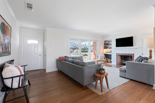 living room featuring built in shelves, a fireplace, ornamental molding, and dark hardwood / wood-style floors