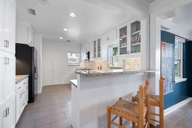 kitchen with stainless steel appliances, a breakfast bar, and white cabinets