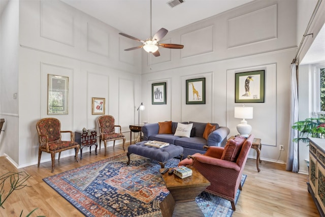 living room with ceiling fan, light hardwood / wood-style flooring, and a towering ceiling