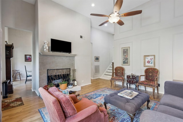 living room featuring light hardwood / wood-style flooring, ceiling fan, and a high ceiling