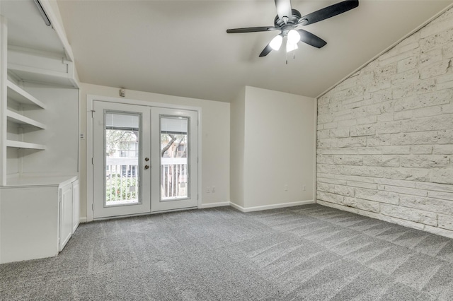 carpeted spare room featuring wooden walls, vaulted ceiling, french doors, and ceiling fan