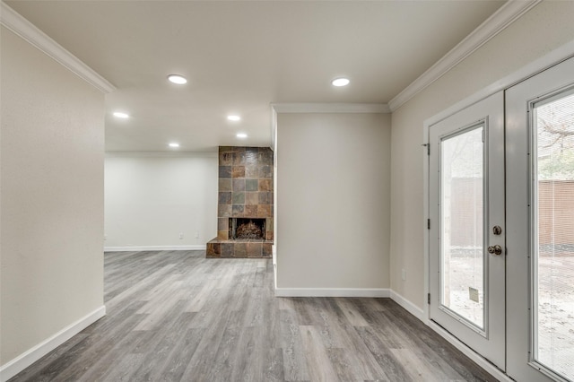 unfurnished living room with french doors, ornamental molding, hardwood / wood-style floors, and a tile fireplace